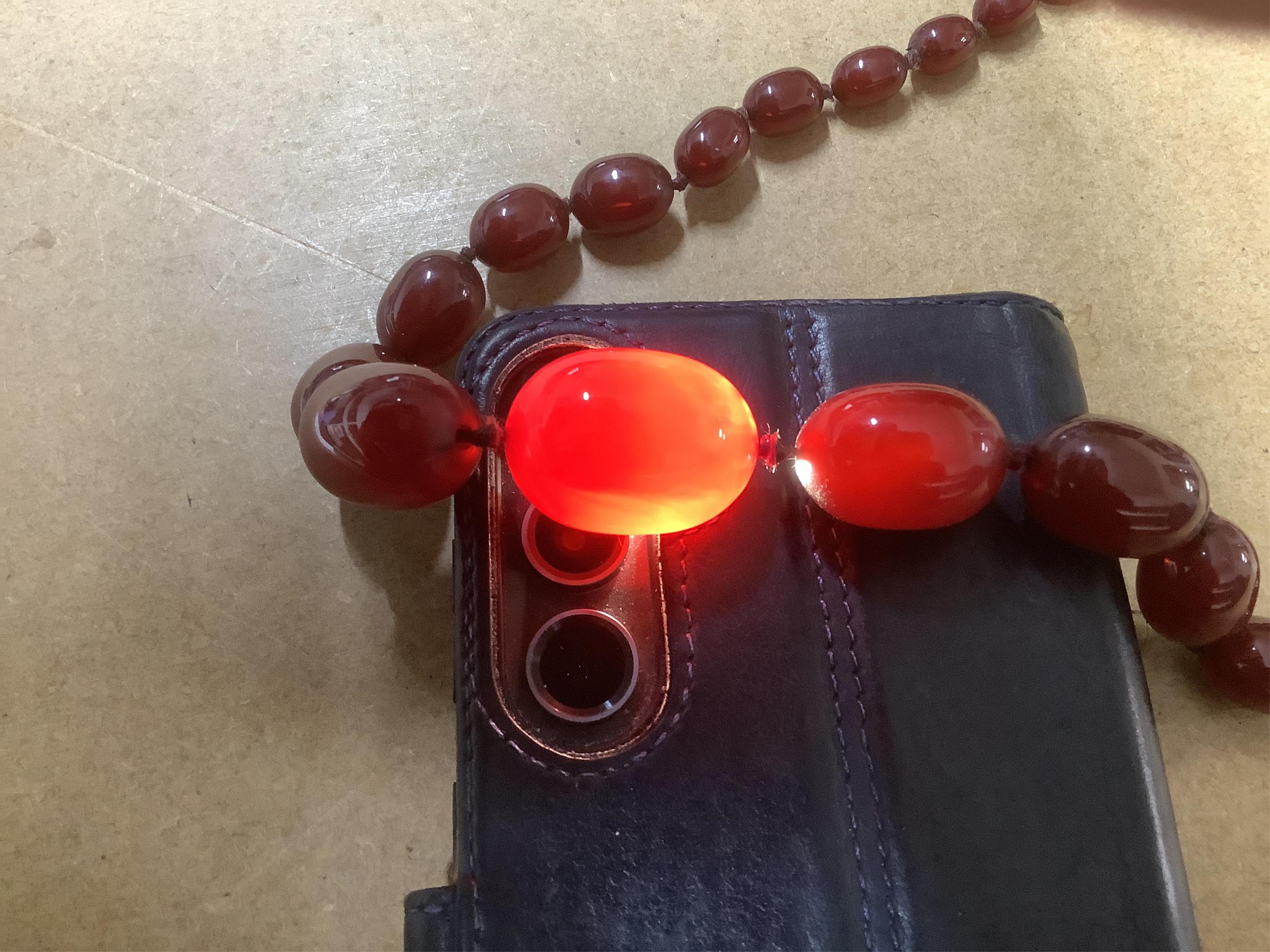 A single strand graduated oval simulated cherry amber bead necklace, 94cm, gross 63 grams. Condition - fair